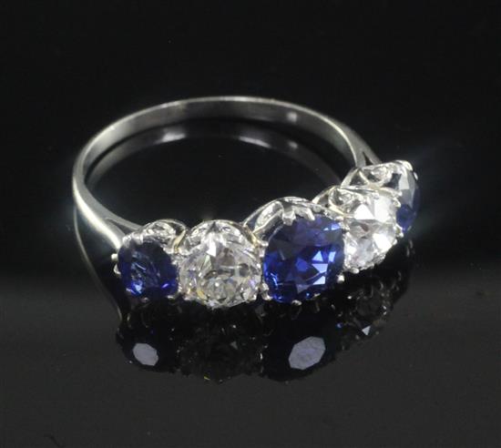 A mid 20th century white gold and graduated five stone sapphire and diamond half hoop ring, size Q.